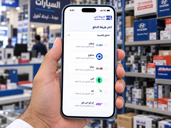 عميل يختار طريقة الدفع بالتقسيط على هاتفه داخل متجر قطع غيار، والقائمة تعرض مزودي قسيمة بلس الستة وعدد دفعات كل منهم